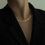 Modern corporate lady in black blazer wearing statement golden choker