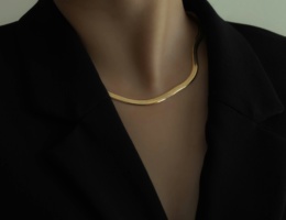 Modern corporate lady in black blazer wearing statement golden choker