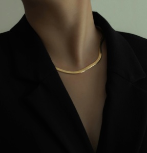 Modern corporate lady in black blazer wearing statement golden choker