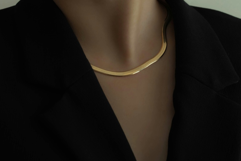 Modern corporate lady in black blazer wearing statement golden choker